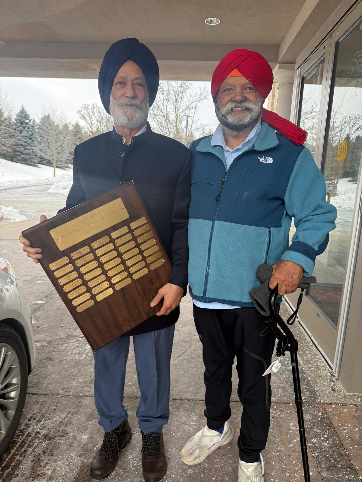 Two men holding the engraved Singh Open Annual Golf Outing winners' plaque