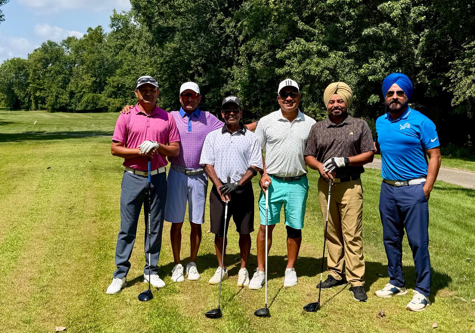 Six golfers posing with their clubs on the tee box on a sunny day