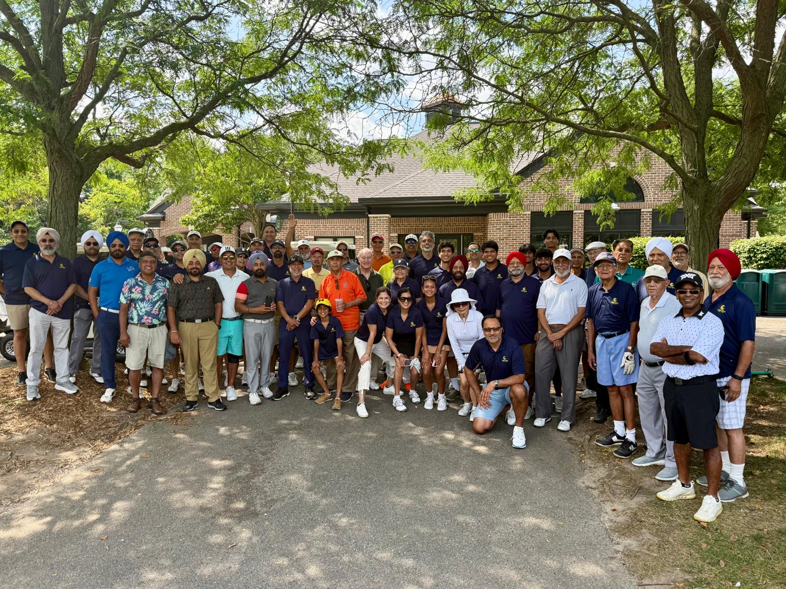 Roughly fifty Singh Open golfers gathered together in front of the clubhouse under the trees