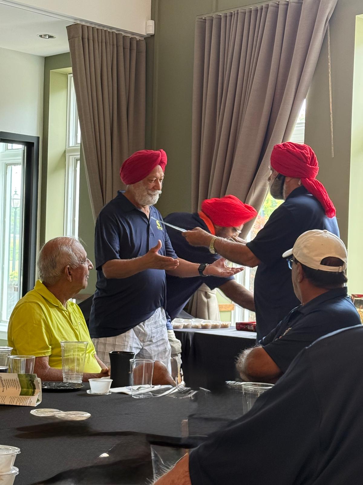 Golfers in red ceremonial turbans during the kirpan ceremony inside the clubhouse