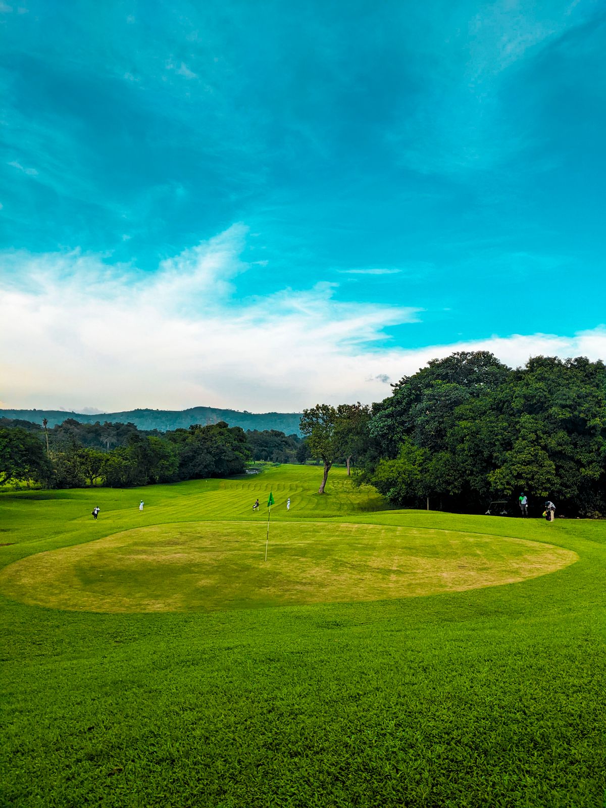 A putting green with the pin flag standing under a dramatic sky